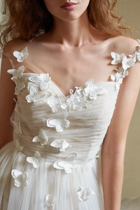 Détail des papillons 3D blancs appliqués sur une robe de mariée élégante en tulle