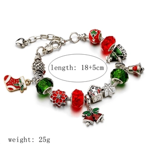 Bracelet de Noël avec perles rouges et vertes et pendentifs festifs sur fond blanc neutre