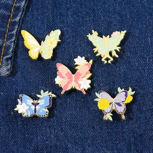 Detailed close-up of colorful floral butterfly enamel pins on blue denim fabric