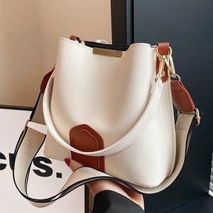 Chic white bucket bag with brown leather accents and a stylish wide woven shoulder strap