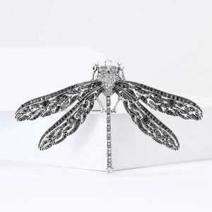 Macro detail of vintage silver dragonfly brooch with black crystals on wings