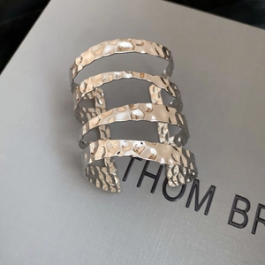 Detail of silver multi-layer cuff bracelet with hammered metal texture and wavy hollow design