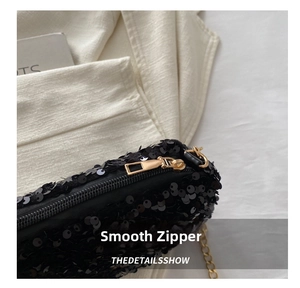 Detail shot of smooth gold-tone zipper and shimmering black sequins on crossbody bag