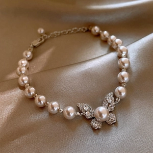 Vista dettagliata di un elegante bracciale di perle con ciondolo a farfalla su seta pura