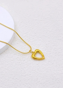 Detail showing gold heart pendant with hollow cutout design on sleek snake chain