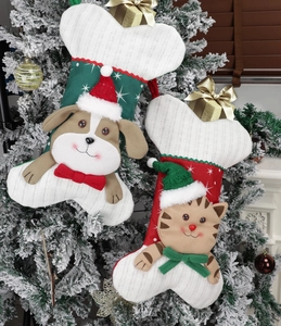 Detailed knit bone-shaped Christmas stockings for cats and dogs hanging on snowy trees