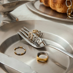 Présentation créative de bagues et boucles d'oreilles en acier et strass sur une fourchette