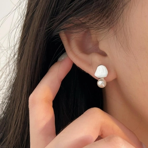 Macro detail of brushed silver pearl stud earring worn on model's ear lobe