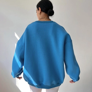 Back view of a blue oversized knitted sweatshirt with drop shoulders and ribbed hem