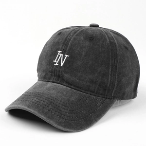 Close-up of white IN letter embroidery on washed black cotton canvas baseball cap
