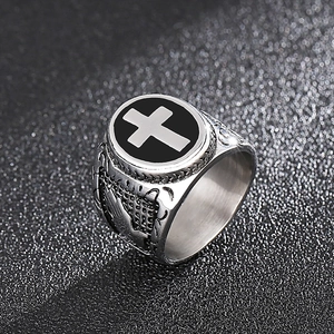 Detail of vintage stainless steel signet ring featuring a black cross with relief patterns