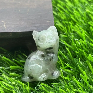 Macro detail of a 1.2 inch hand-carved natural stone cat figurine on green grass