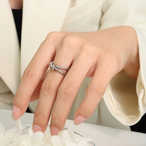 Macro shot of a minimalist silver knot ring in stainless steel on a model's finger