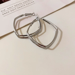 Detail view of silver double-layered geometric square earrings on a beige card