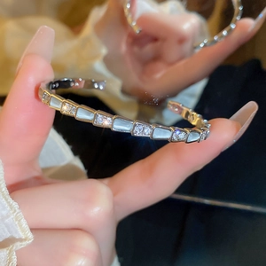 Detail of gold snake scale bracelet with inlaid white shells and sparkling zircons