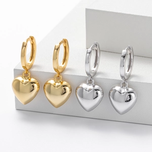 Detailed view of gold and silver heart-shaped hoop earrings on white geometric stands