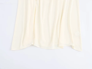 Close-up of cream white dress hem showing silky fabric texture and neat sewing craft