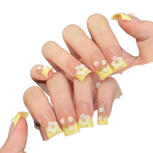 French style yellow press-on nails with 3D white flower accents on a white background