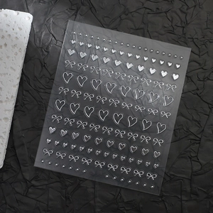 Detailed view of silver 3D embossed nail art stickers with heart and bow patterns