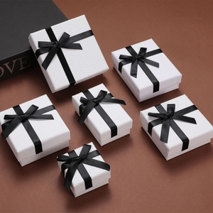 Detailed view of six white jewelry gift boxes with black ribbon bows in various sizes
