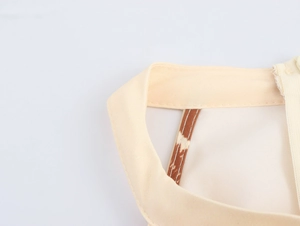 Detail of beige sleeveless dress neckline with white side zipper and fine stitching