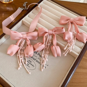Detailed shot of pink fabric bow and tulip tassel jewelry set in a wooden box