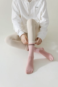 Detailed view of pink five-toe yoga socks with striped cuffs and breathable cotton material