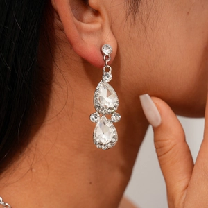 Macro shot of silver-colored teardrop pendant earrings with rhinestones on a model
