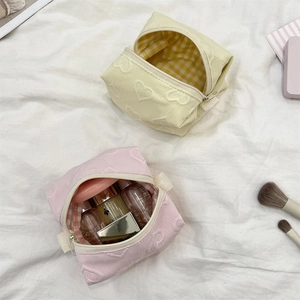 Détail de jolies trousses de maquillage à cœurs gaufrés rose et jaune avec doublure