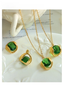 Detail of vintage emerald crystal pendant and earring set on gold chain over books