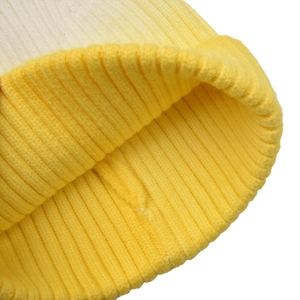Close-up of winter knit beanie showing yellow and cream ribbed weave texture