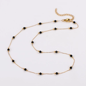 Détail du collier doré avec perles noires facettées et fermoir mousqueton ajustable