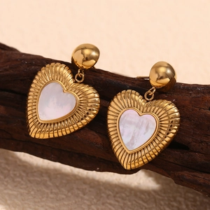 Vue macro de boucles d'oreilles cœur en plaqué or 18K avec nacre sur support bois