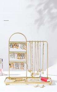 Detail of golden iron jewelry rack with earring holes, hooks and glass base tray