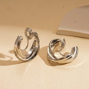 Macro shot of silver spiral metal clip-on earrings on gray stone with a warm background