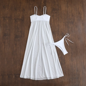 Detailed flat lay of white mesh two-piece bikini set with sheer long skirt on wood background