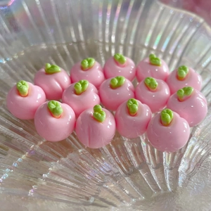 Dettaglio di ciondoli di pesche in resina rosa 3D con foglie in ciotola lucida