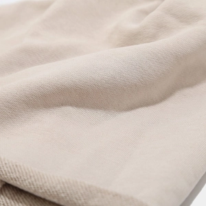 Close-up of light beige knitted fabric texture showing premium soft cotton fibers