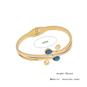 Macro detail of golden stainless steel snake bracelet with blue teardrop stones
