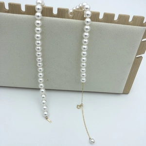 Detailed shot of round white pearls with a 14k gold-filled adjustable clasp on a stand