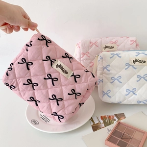 Detailed macro view of quilted bow pattern makeup bags in pink and white fabrics