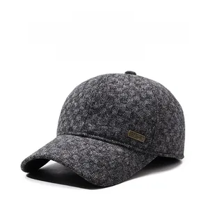 Detailed view of grey herringbone wool baseball cap with ear flaps and metallic logo