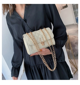 Detail of quilted creamy white crossbody bag with gold chain strap and metal lock closure