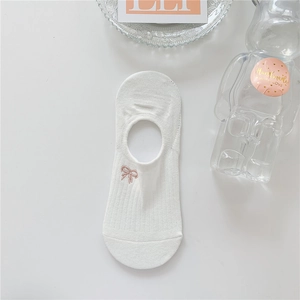 Close-up of a white cotton no-show sock with a delicate pink bow embroidery detail