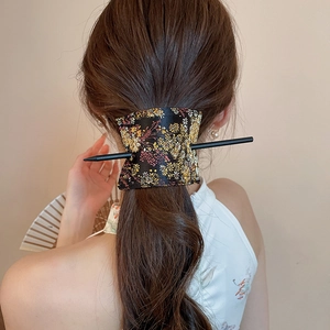 Detail of handmade floral embroidery fabric and black minimalist hairpin on hair