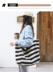 Detailed view of wide black and white striped canvas tote bag worn on shoulder