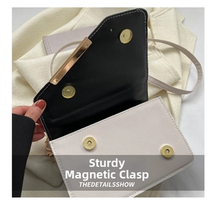 Dettaglio della chiusura magnetica e finiture dorate su una borsa a tracolla bicolore