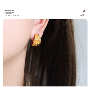 Close-up of vintage U-shaped 18K gold-plated earrings with unique threaded texture