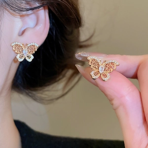 Detail of gold-plated butterfly earrings with cubic zirconia on a model's ear