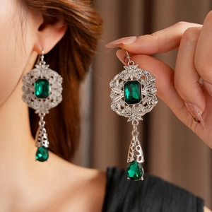 Macro detail of vintage style long earrings with green stones and silver floral patterns